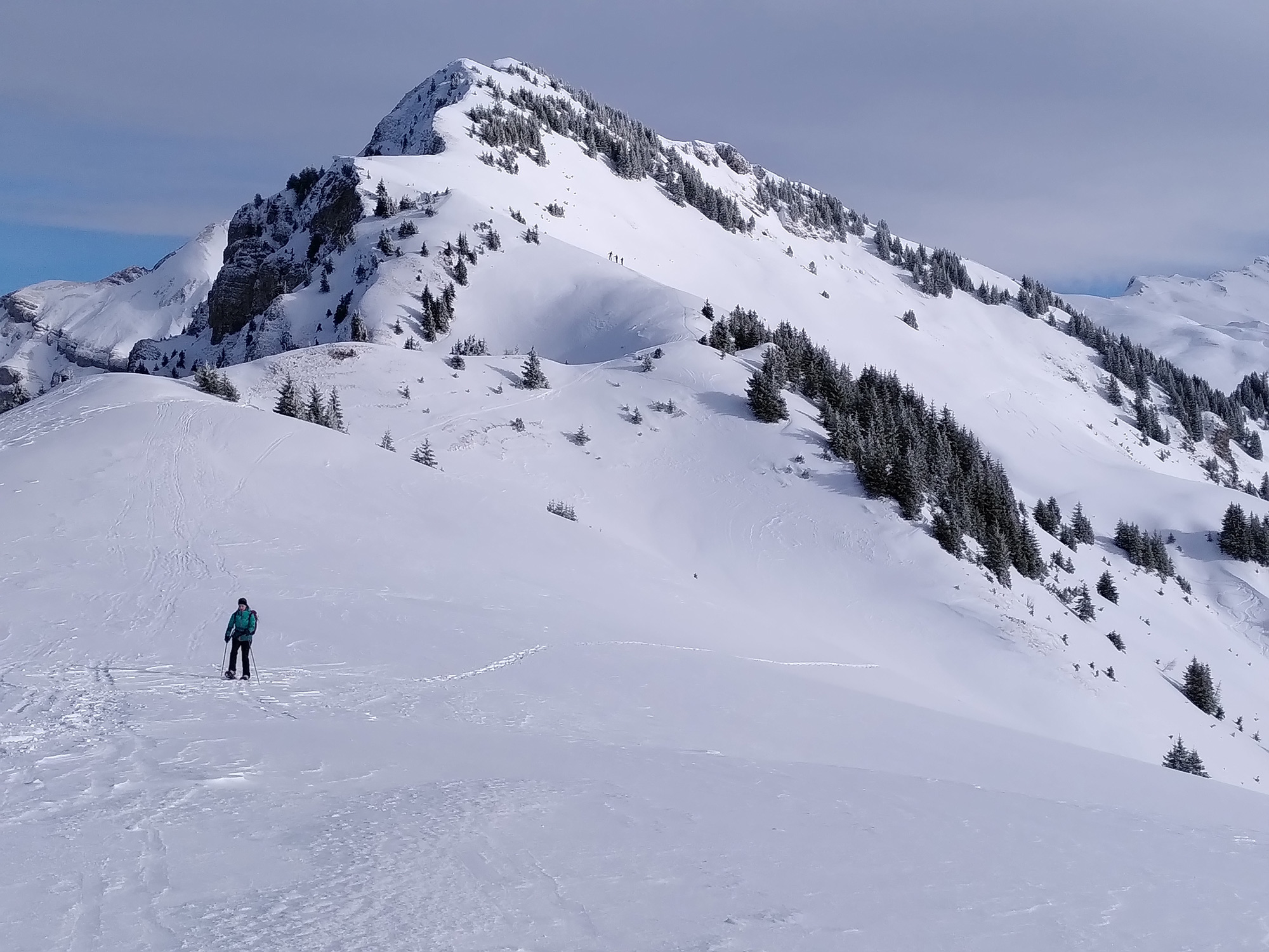 Eine einsame Wanderin mit Schneeschuhen - im Hintergrund der Gipfel und alles voll schönem weissen Schnee. 