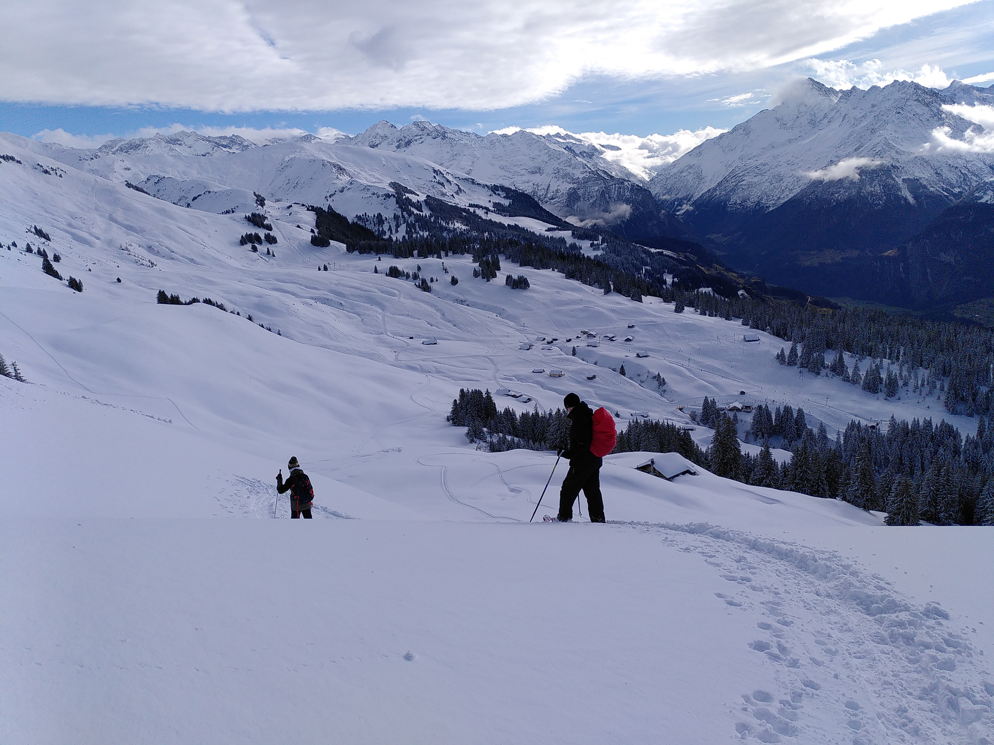 Auf dem Abstieg mit den Schneeschuhen vor wunderschönem Panorama mit schneebedeckten Bergen. 
