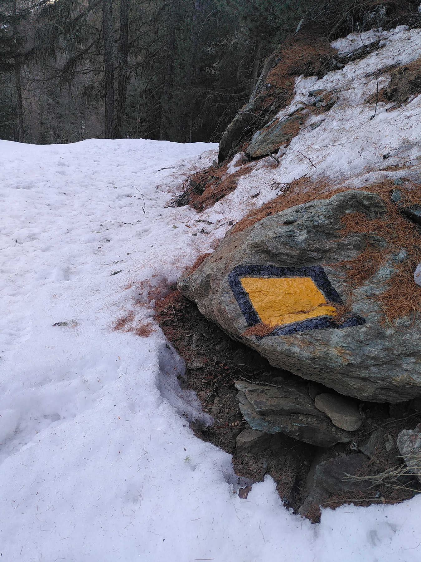 Ein Wegweiser auf einen Stein gemalt auf der Tour - daneben Schnee. 