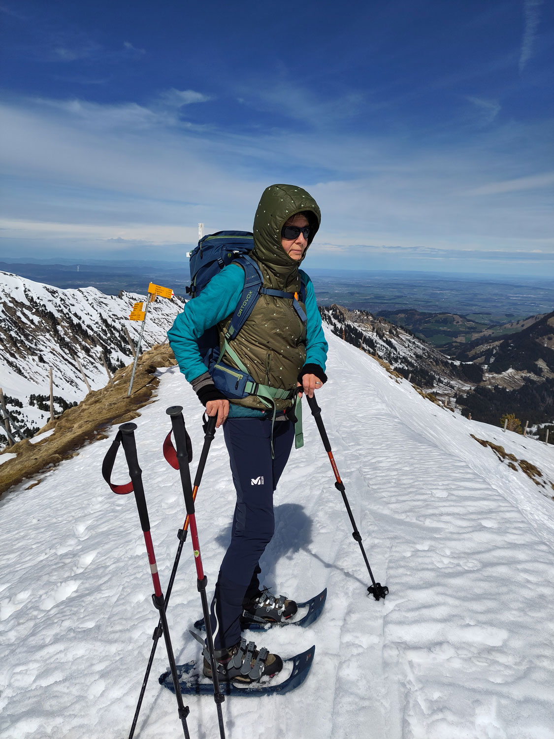 Wanderin auf dem Gipfel mit Schneeschuhen und schönem blauen Himmel in der Ferne.